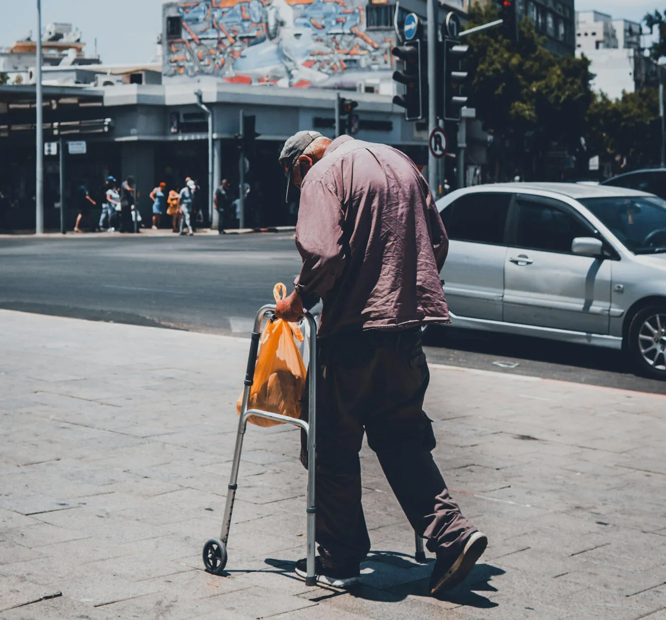 A man walking on the sidewalk with a walker